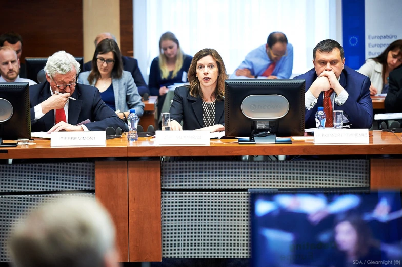 a bunch of people sitting at a table having a meeting