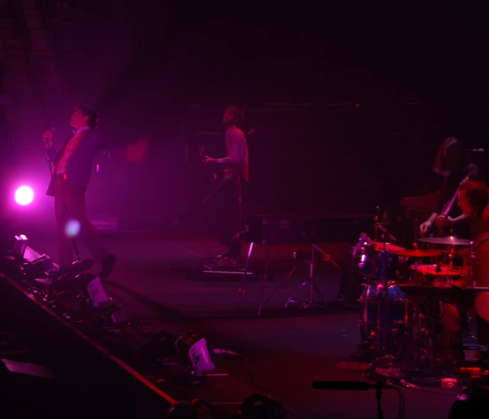 two people are standing in a dark room as the band plays