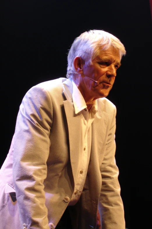 an old man standing in front of a black background