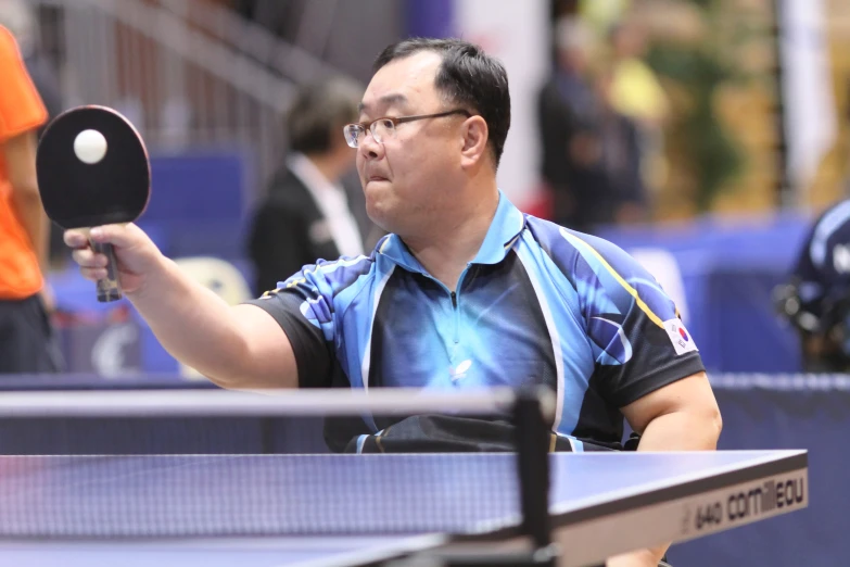 a male tennis player holding a ping pong paddle