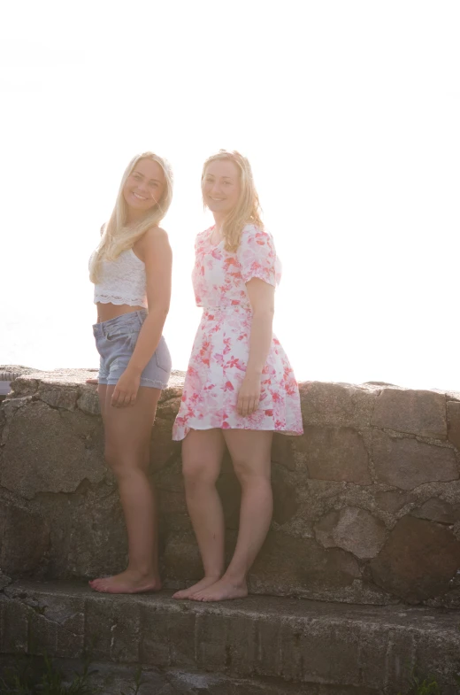 two girls stand next to each other at the water