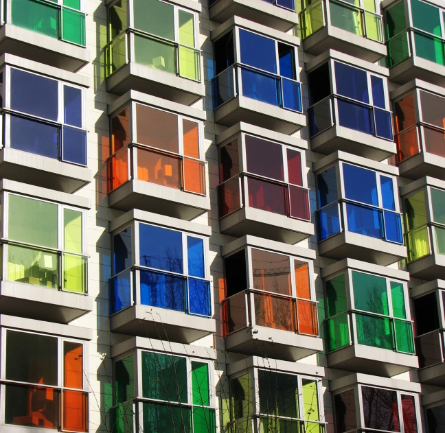 the windows of a tall building are made out of many different colors