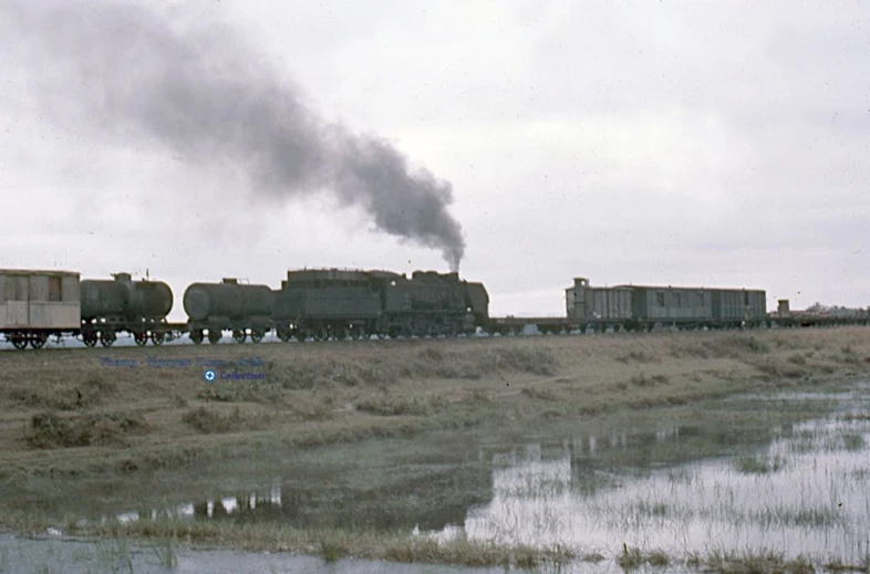 a freight train making a crossing over a flooded ditch