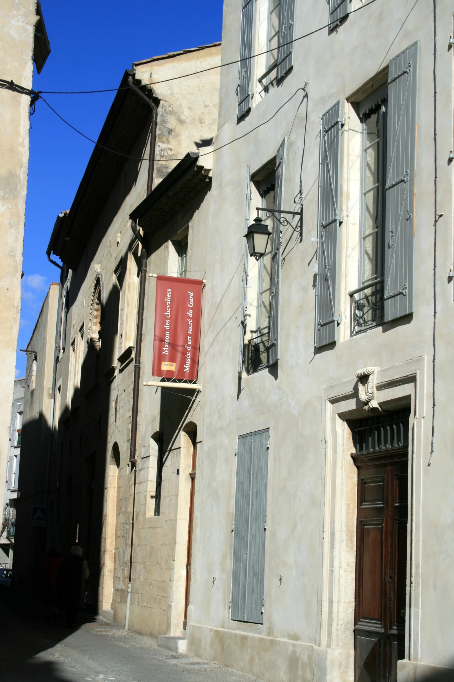 a grey building with black shutters and windows