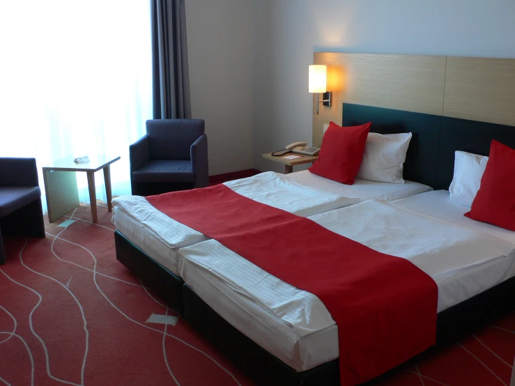 a el room with red and white sheets and pillows