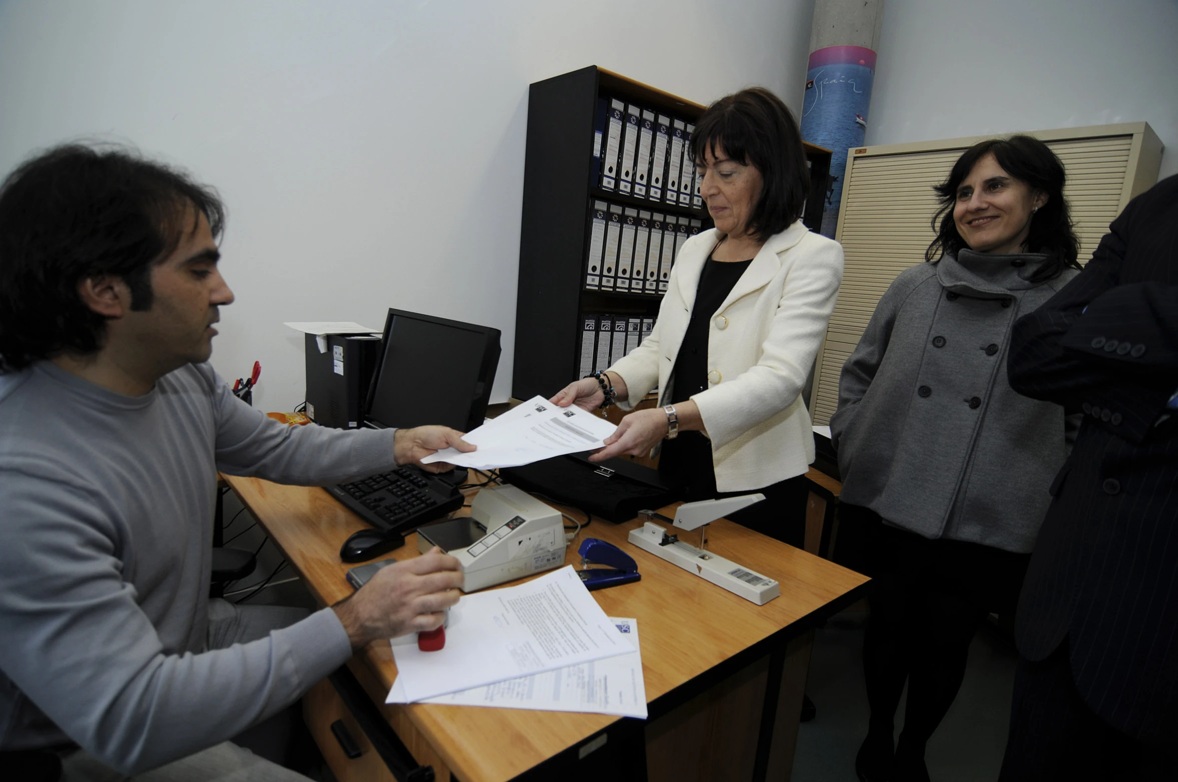 two woman standing in an office talking to two men