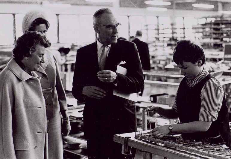 three people in a factory looking at soing on a board