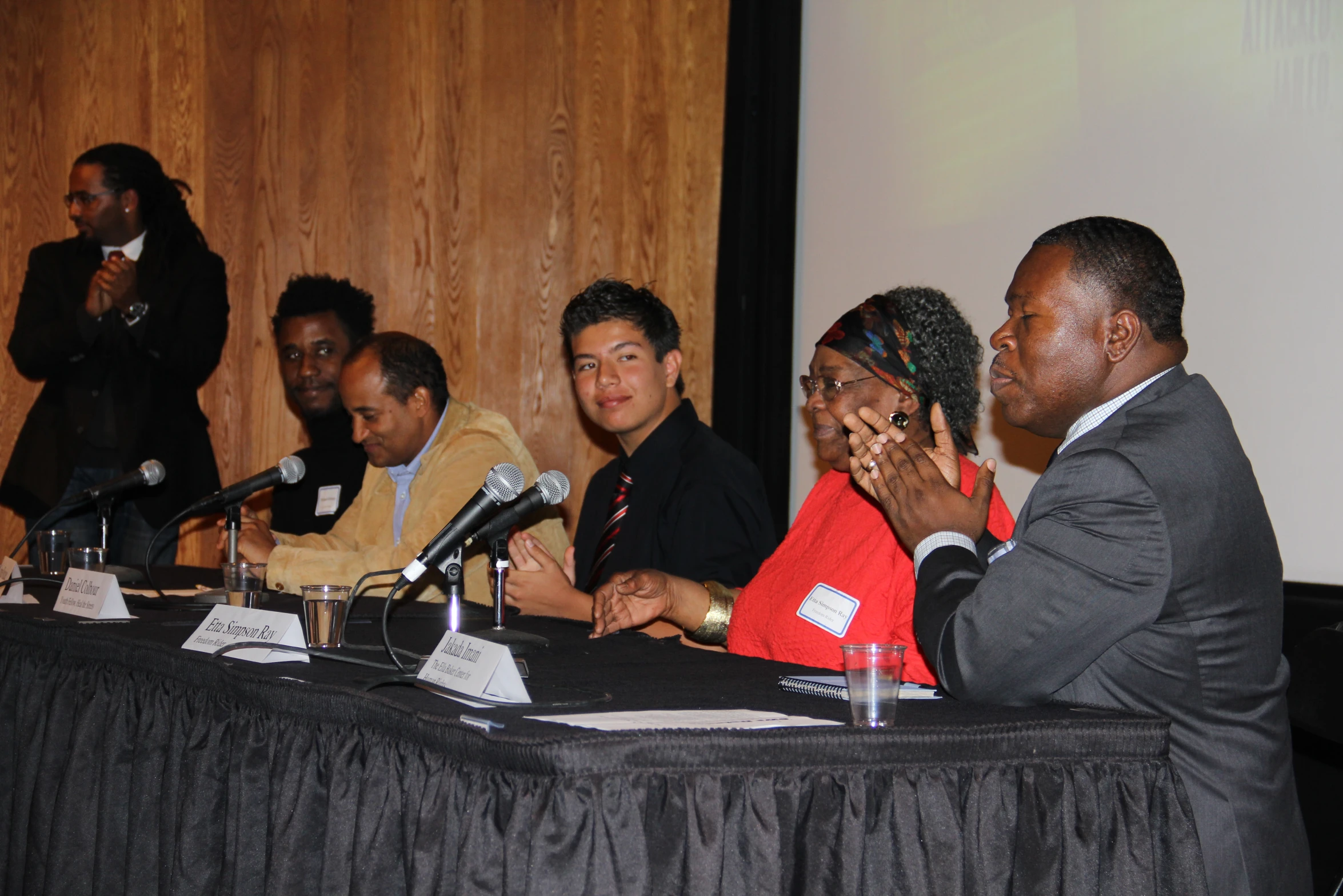 several people sitting at a table together in front of microphones