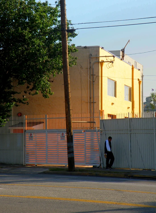 two men are walking past a fenced in building