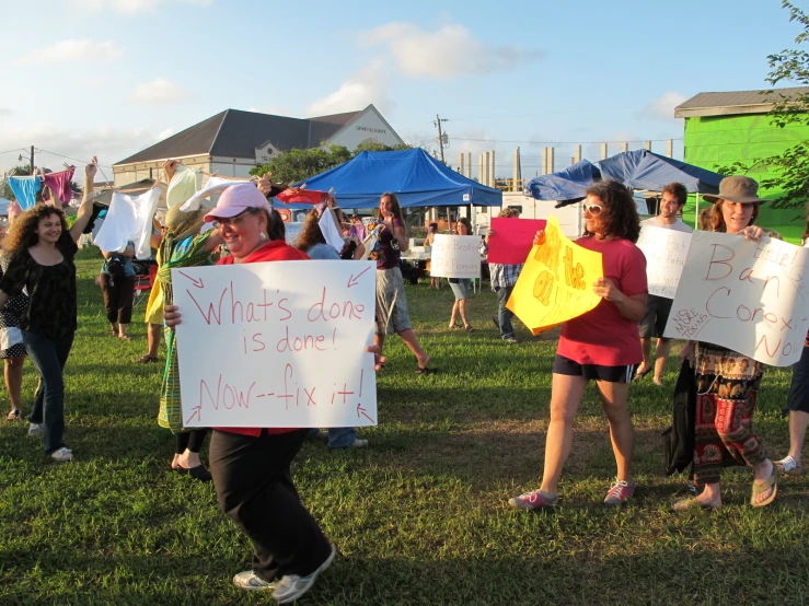 some people with signs holding umbrellas in a park