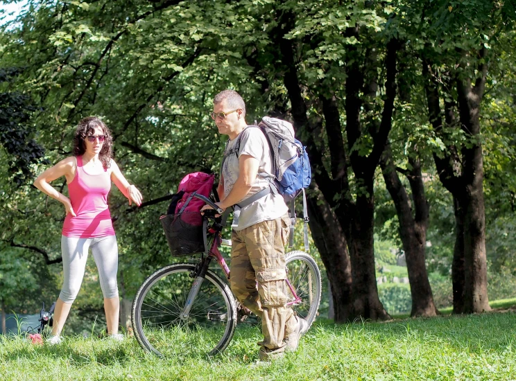 a man and woman stand near bicycles while one man talks on his cell phone