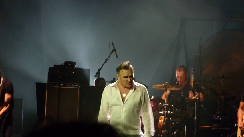 a man in a white shirt standing next to two guitars