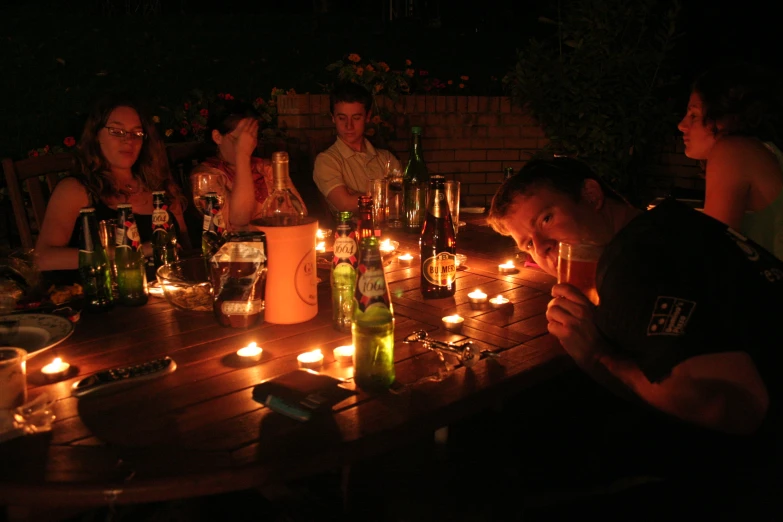 there is a group of people sitting at the table with candles lit