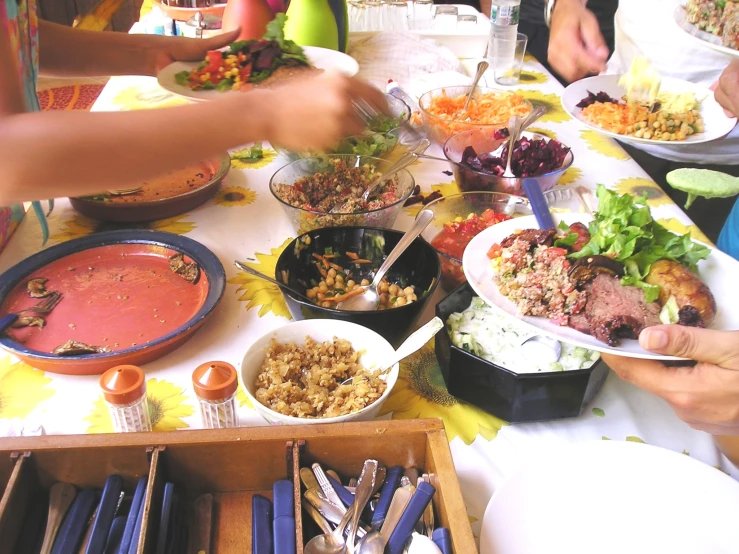 many people are gathering around plates with food