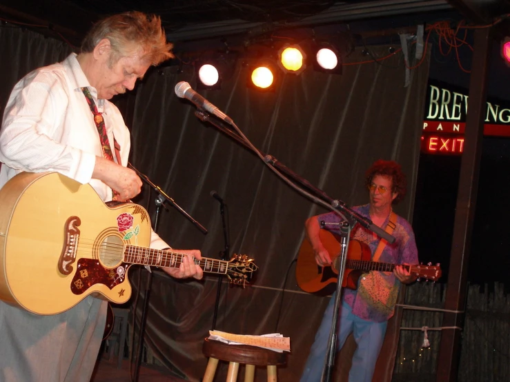 a person that is playing a guitar in front of a microphone