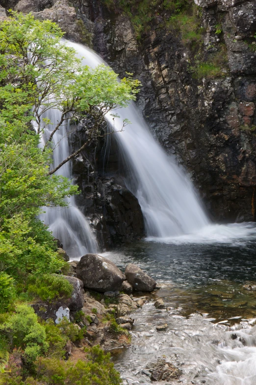 a stream running into a lush green hillside