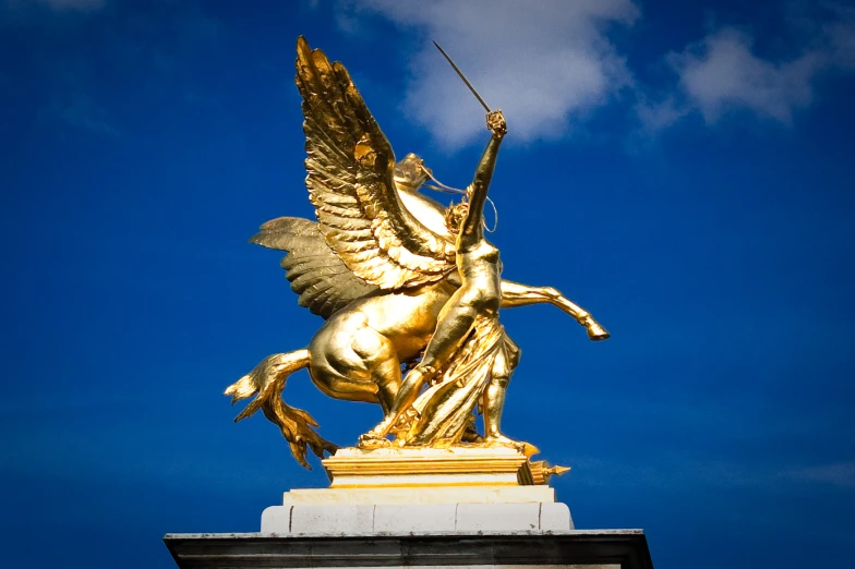 a golden statue of a horse with wings and a spear