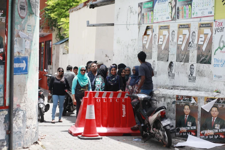 the people are gathered together beside a construction barricade