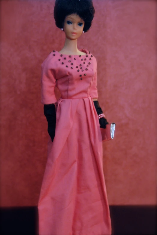 a barbie doll with a pink dress and black gloves