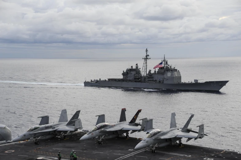 two fighter jets on an aircraft carrier in the ocean