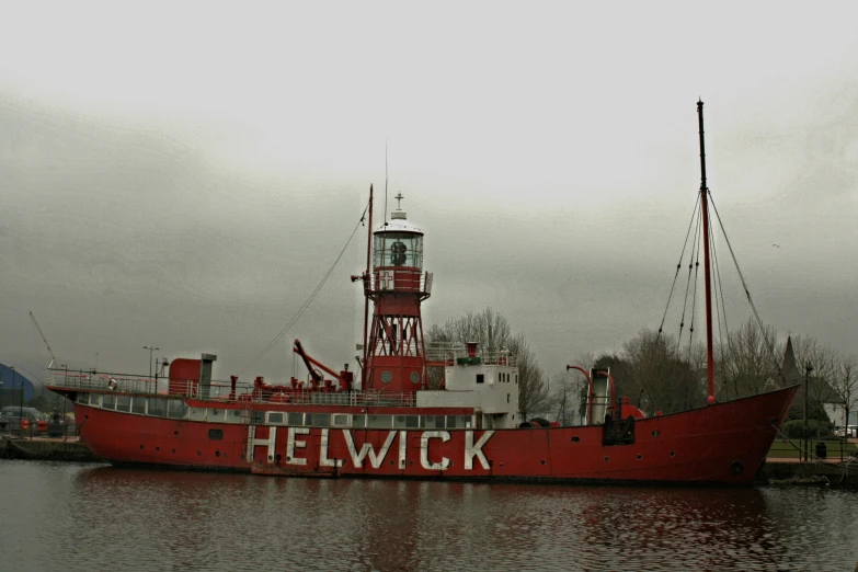 a red ship floating in the water with a tower