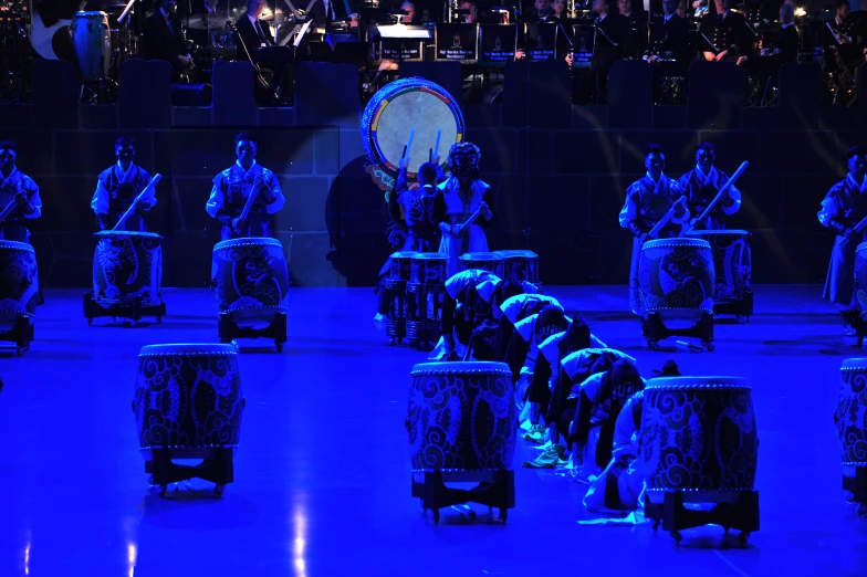 a group of men play drum on stage while people watch