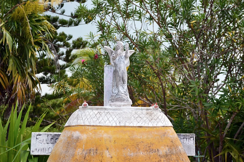 a statue in front of trees with other plants