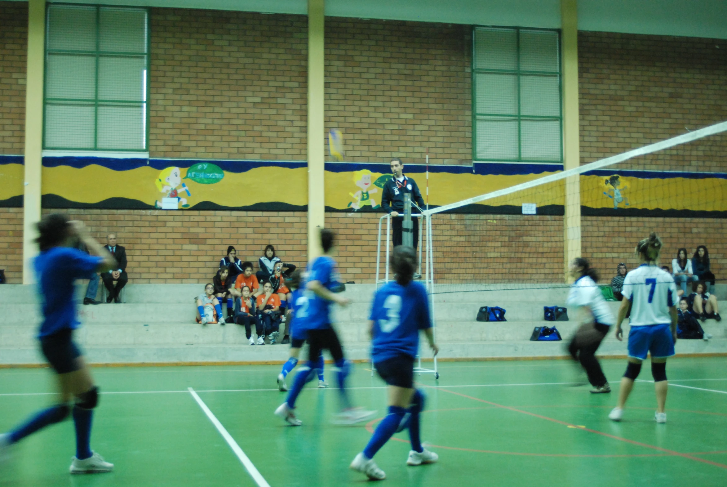 a group of people playing volleyball in a gymnasium