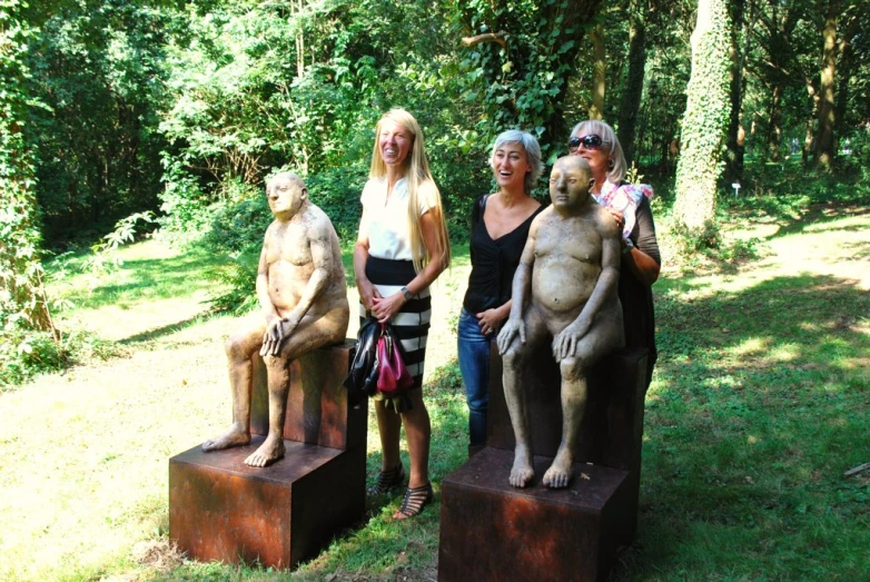 people standing around statues in the woods