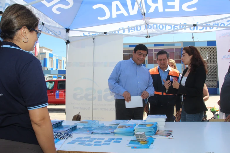 two men and a women looking at an informational display under a tent
