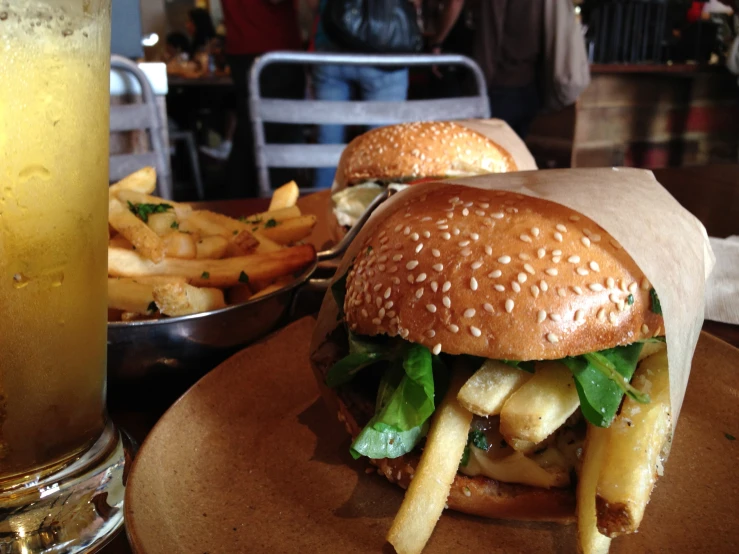 a hamburger with french fries is on a table near a drink