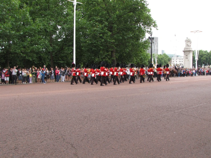 many men in red uniforms marching on street with group behind