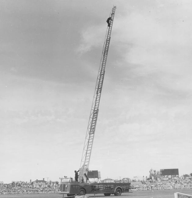 black and white pograph of man sitting on top of crane