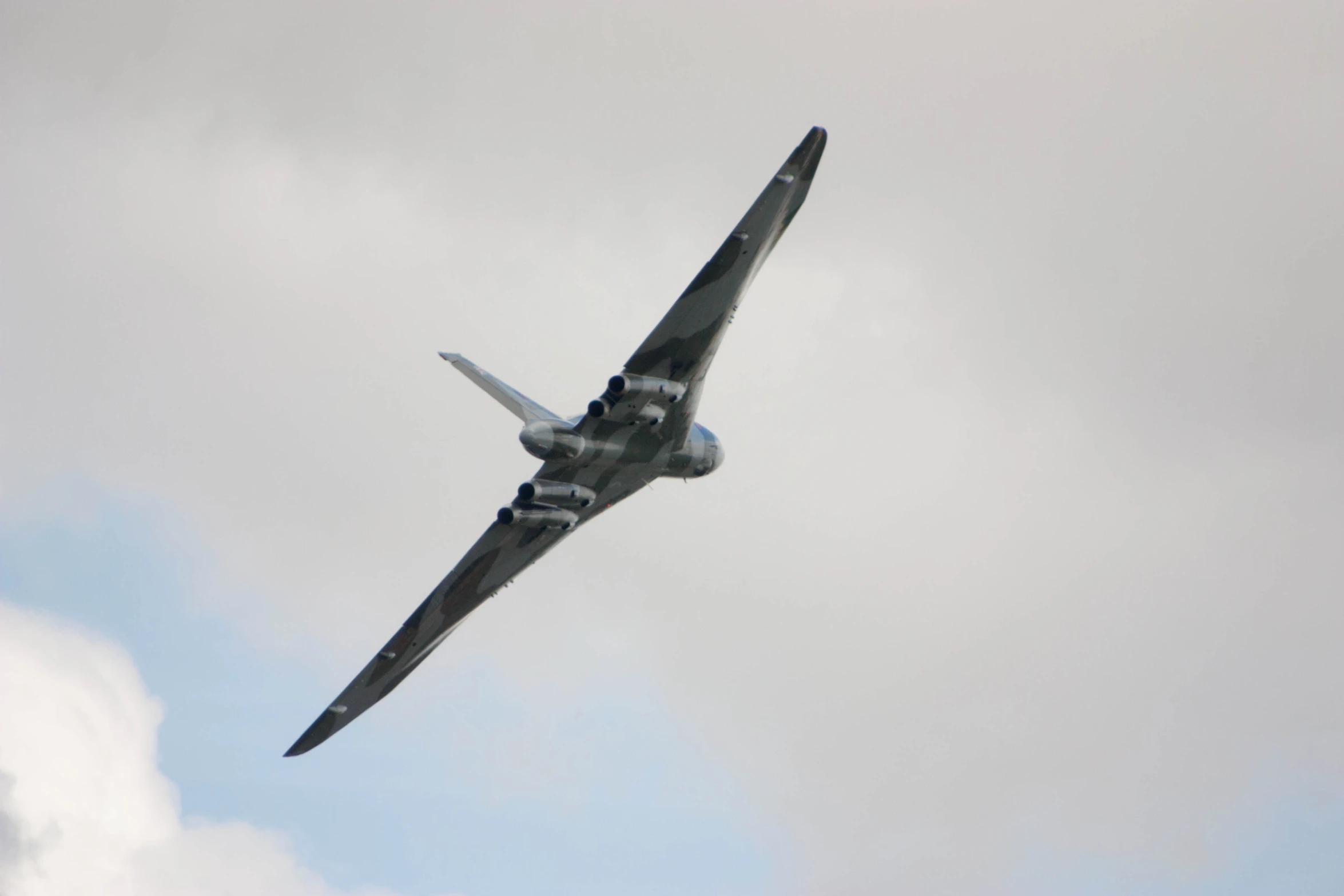 a plane flies through the air in a gray sky