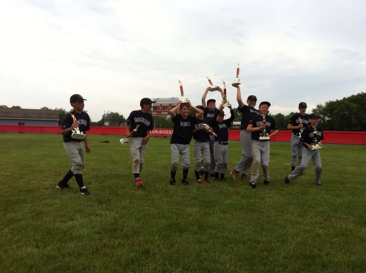 baseball players in their uniforms holding up trophies on the field