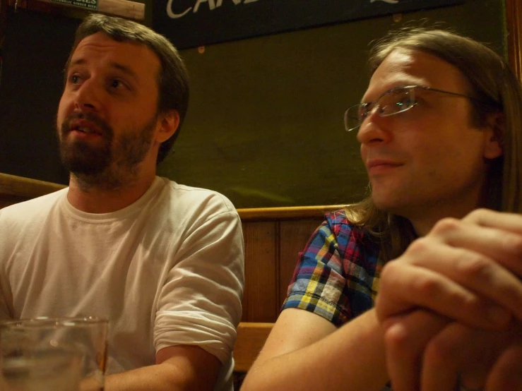 two men sitting next to each other at a table