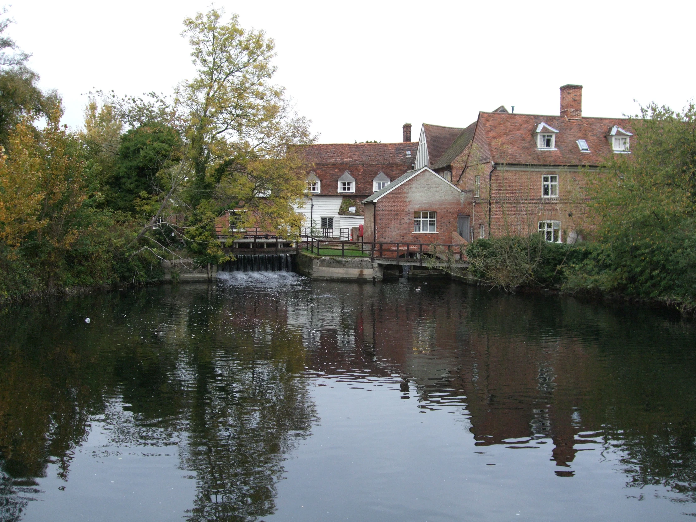 old brick building by river with reflection in water