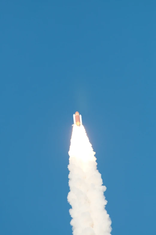the rocket is leaving a trail as it flies in the blue sky