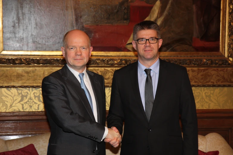 two men wearing suits and ties shaking hands