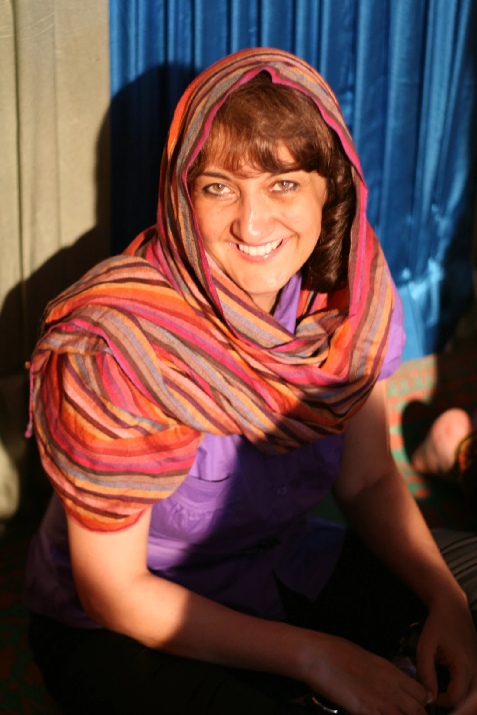 the woman is wearing an orange, pink and green shawl