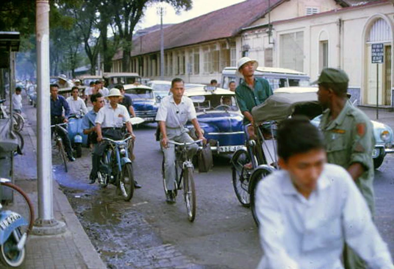 a group of bicyclists and cars riding down the street