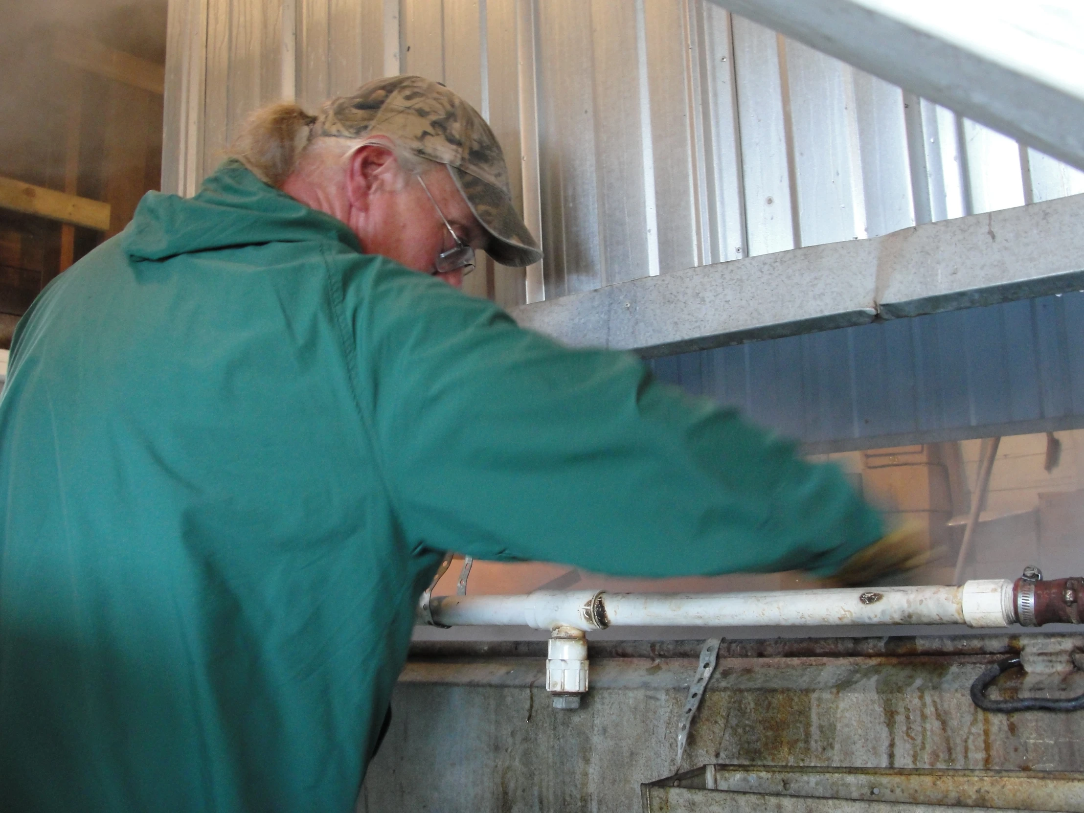 a man with a green coat stands at a line and puts soing on a tank