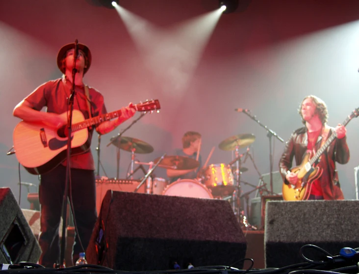 two men in red shirts and cowboy hats playing guitar