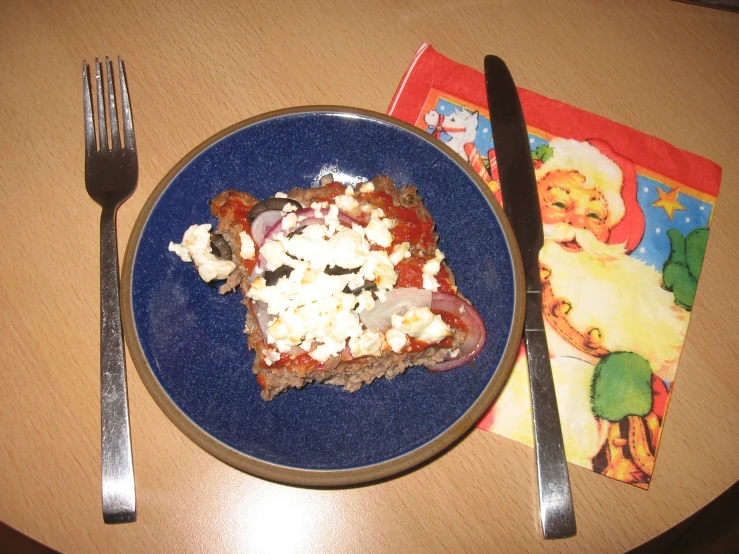 a plate with pizza sitting on top of it next to silverware and a napkin