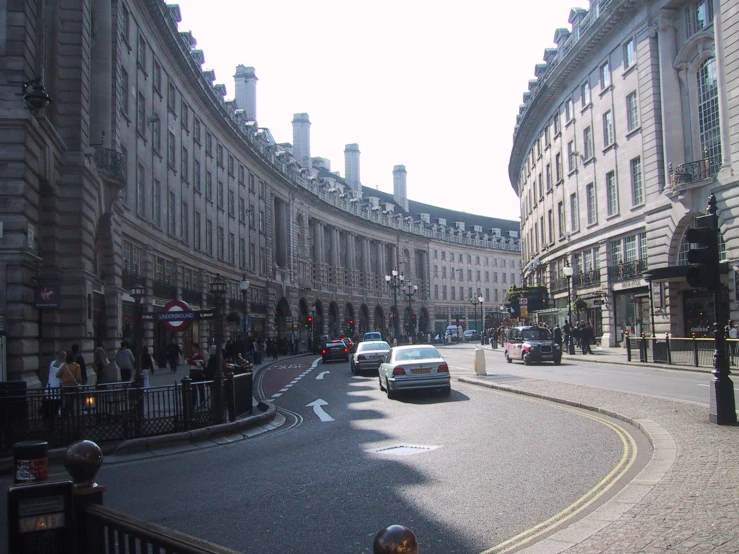 cars drive down a quiet streets lined with buildings