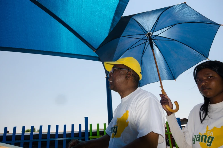 a man and woman standing under umbrellas in the sun