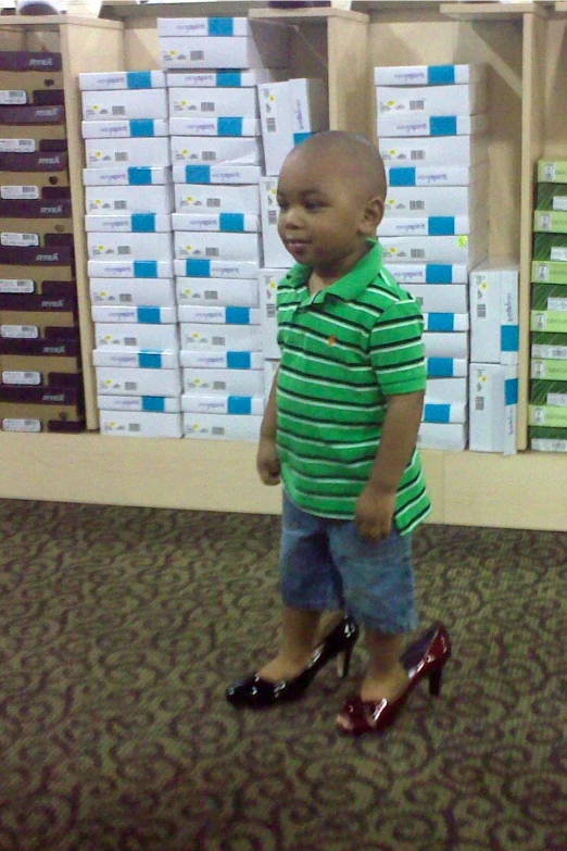 a little boy in green shirt standing in the middle of a room