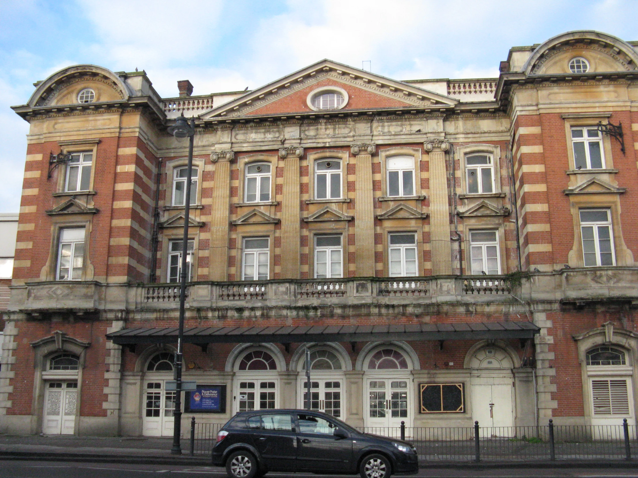 a brown and brown building sitting next to a black car