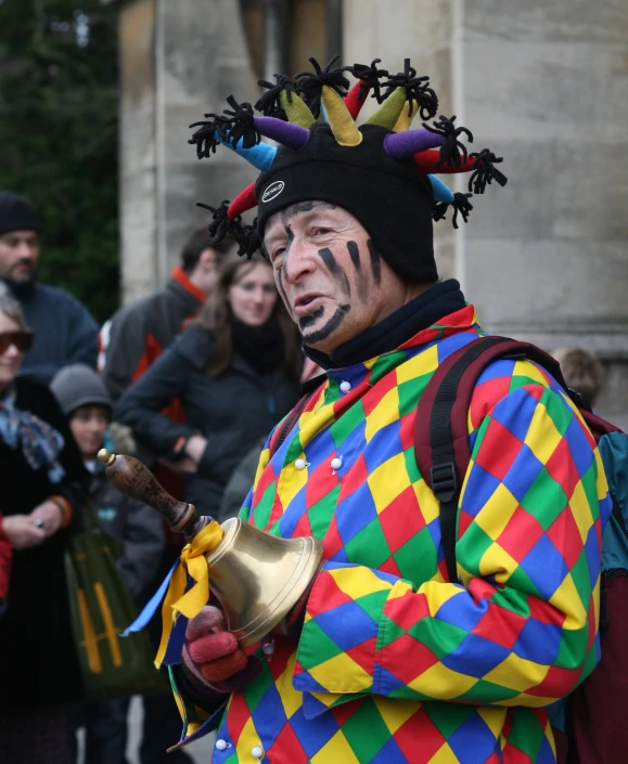 a clown with painted head and tail holding a jug in front of a crowd