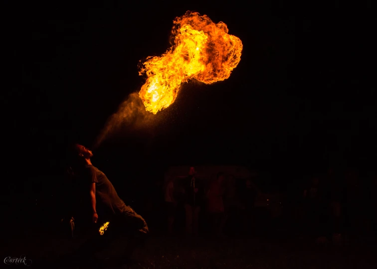 a man in the dark reaching up to a large fire